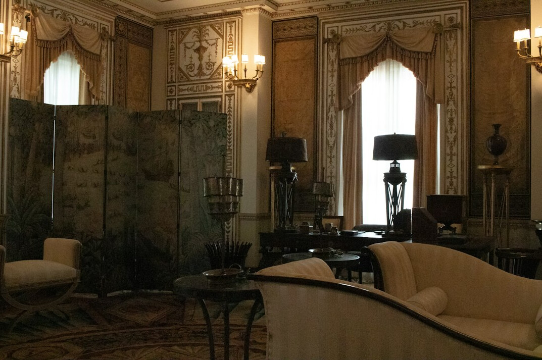 Elegant 1990s-style celebrity living room with velvet armchairs, brass lamps and large windows
